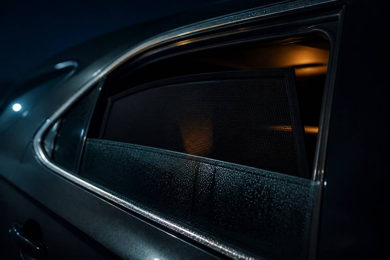 Fenêtre de voiture légèrement ouverte la nuit avec grillage de ventilation